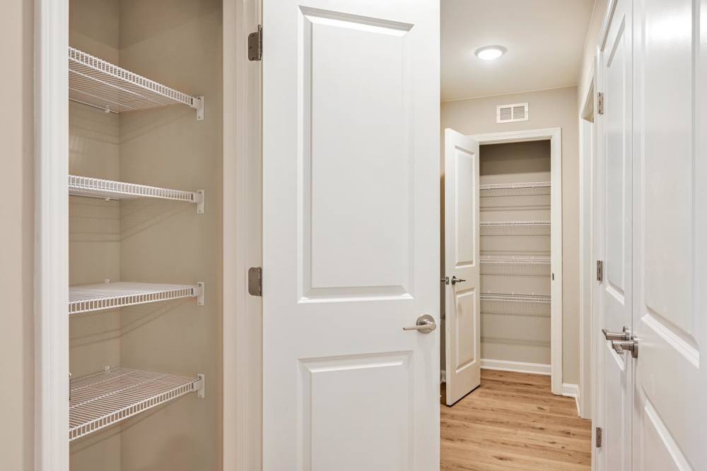 Spacious closets with wire shelving and wood-style flooring in a well-lit hallway at Hawkins Pointe in Hendersonville, North Carolina