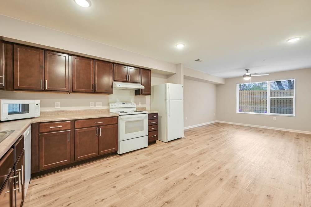 Open layout kitchen with dark wood cabinets, stainless steel appliances, and wood-style flooring at Hawkins Pointe in Hendersonville, North Carolina