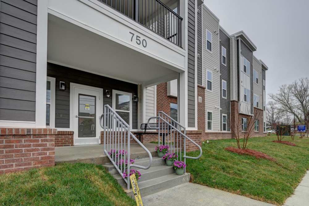 Modern apartment community entrance with welcoming flowers and accessible ramp at Hawkins Pointe in Hendersonville, North Carolina