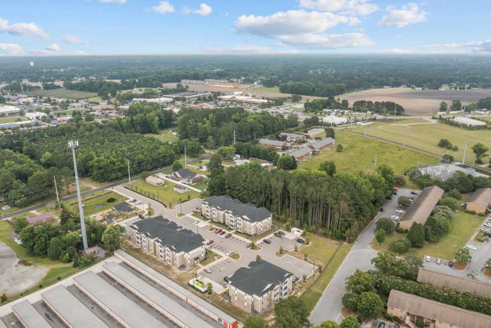 Aerial view of apartment community surrounded by green trees and open fields at Old Firetower Place in Greenville, North Carolina