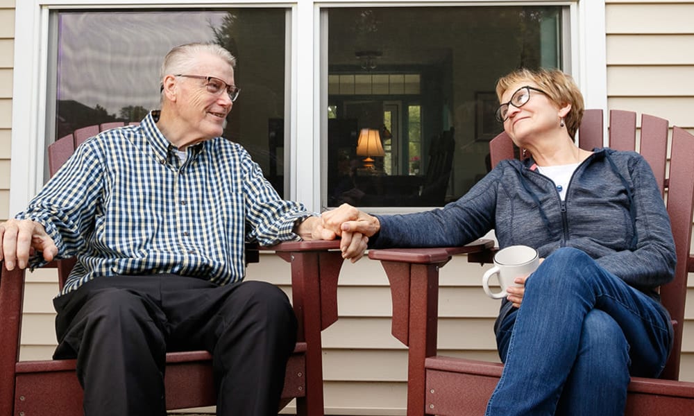 Residents sitting on a porch holding hands.