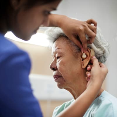 Assisted living resident getting some help from a licensed nurse with her hearing device at Cascade Park Vista Assisted Living in Tacoma, Washington