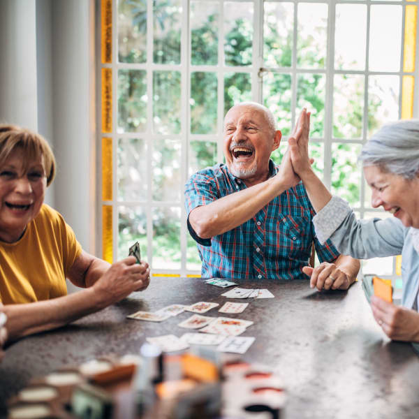 Three residents playing a card game at Pacifica Senior Living South Coast in Costa Mesa, California