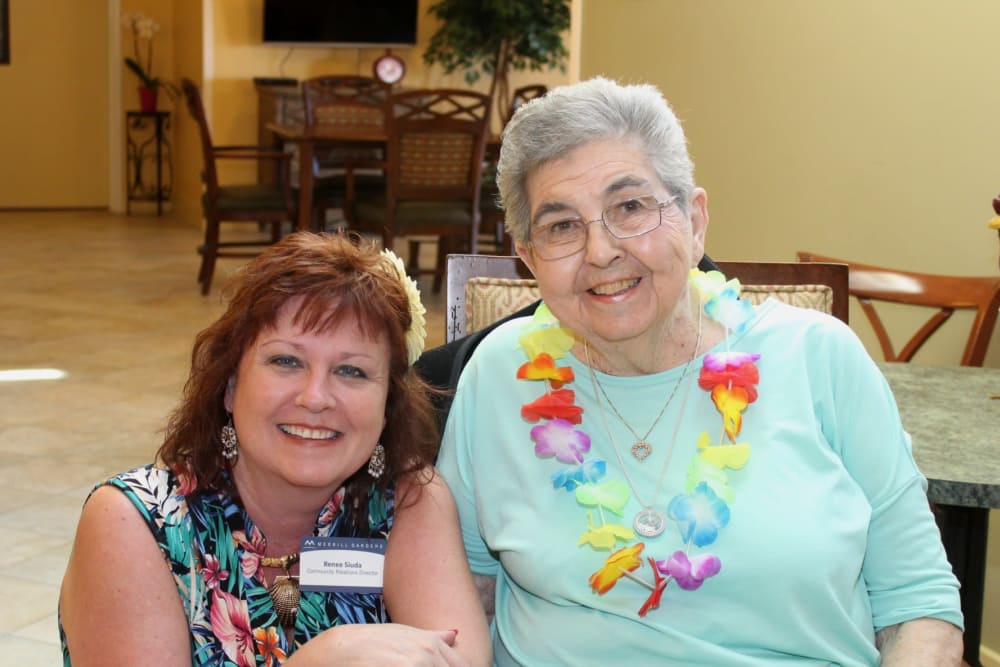 A resident and staff member at a luau at The Oaks, A Merrill Gardens Community in Gilbert, Arizona.