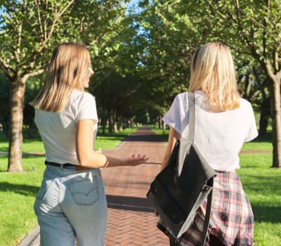 Resident friends walking through the lush neighborhood at Rivers Pointe Apartments in Liverpool, New York