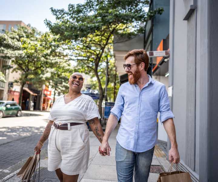 A man and woman walk together coming from shopping near The Acacia in Palo Alto, California