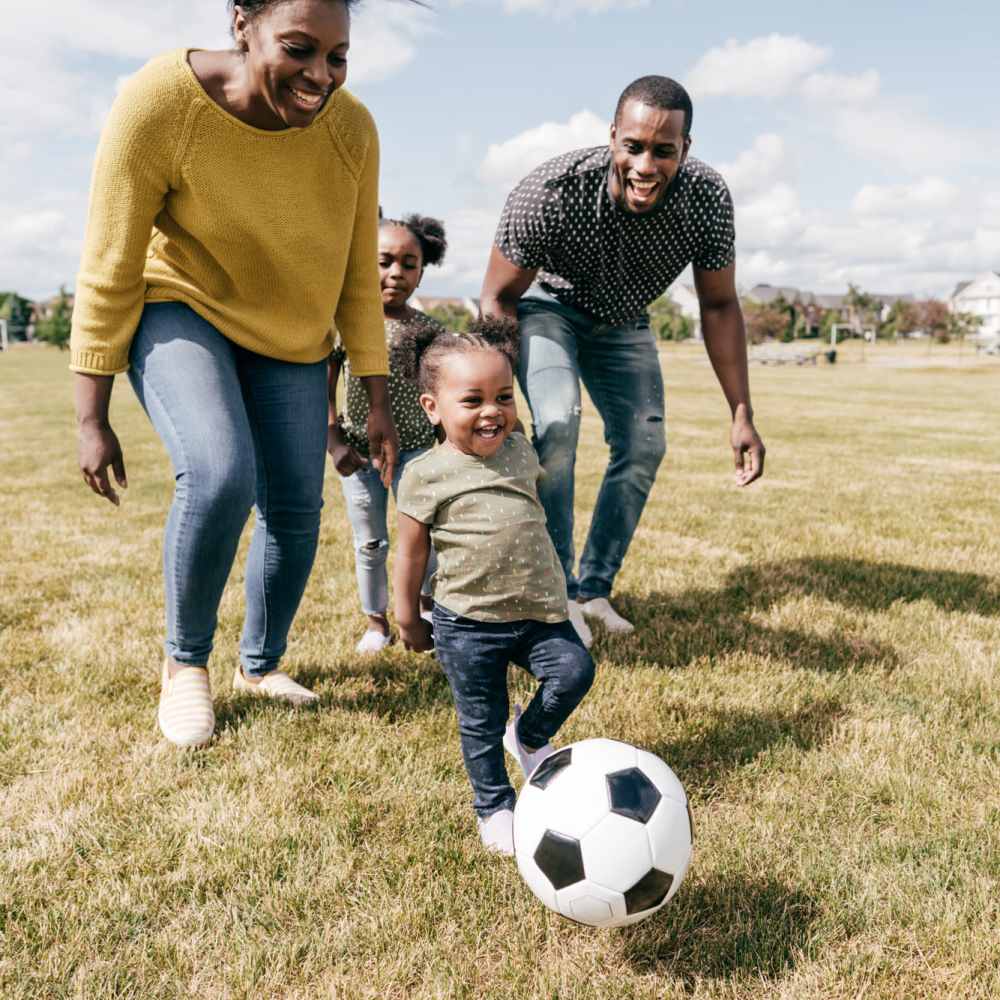 Happy family playing football at Fawn Haven Apartments in Butler, Indiana