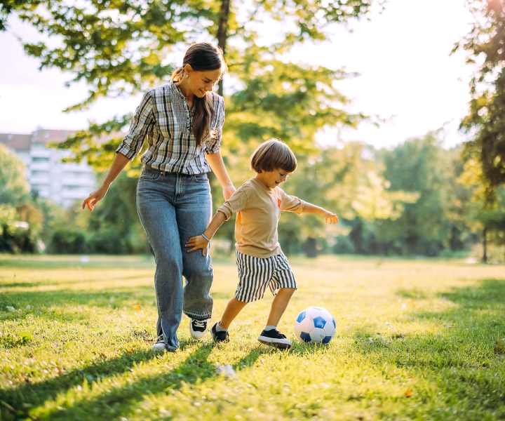 Resident playing football with her son in a park at Cape Fear Townhomes in Fayetteville, North Carolina