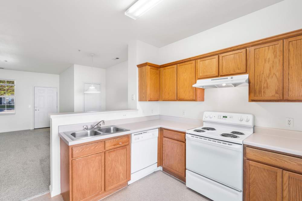 Classy kitchen with brown cabinetry, stainless-steel sink setup at The Reserve at Norton Shores in Norton Shores, Michigan