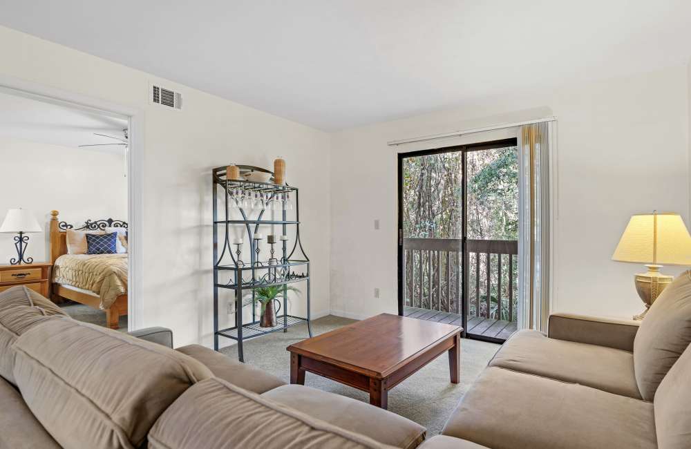 Living room with sectional couch, coffee table, and sliding glass door at Treehouse Village in Gainesville, Florida