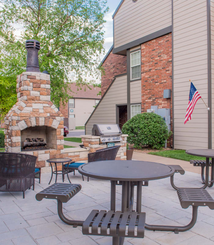 Exterior BBQ grill area with tables at Huntington Park Apartments in Wichita, Kansas