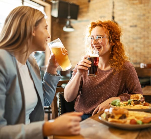 Two women smiling and holding drinks in a restaurant near The Courts of Avalon in Pikesville, Maryland