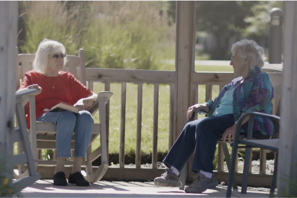 Two residents sitting outside on a sunny day at a Anthology of Clayton View community