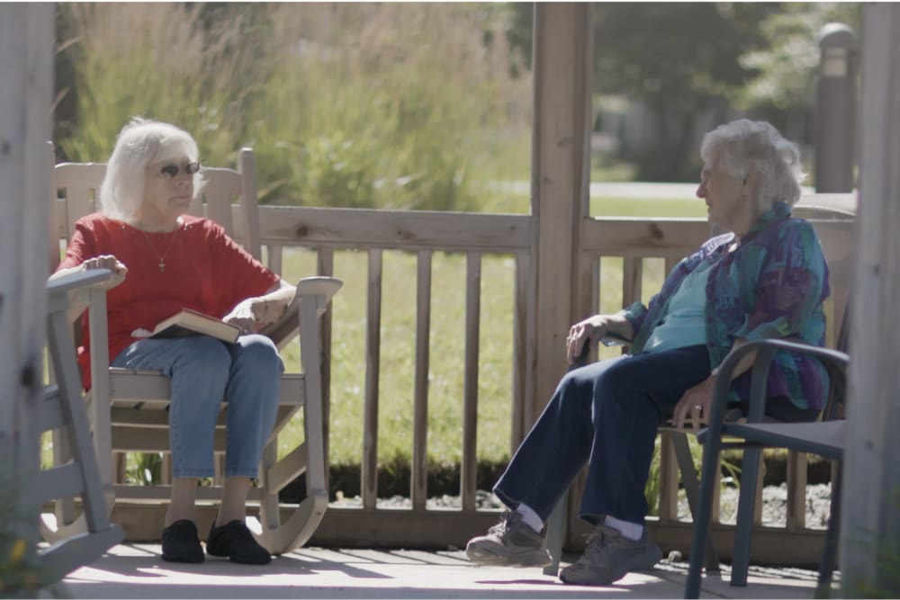 Two residents sitting outside on a sunny day at a Anthology of Blue Ash community