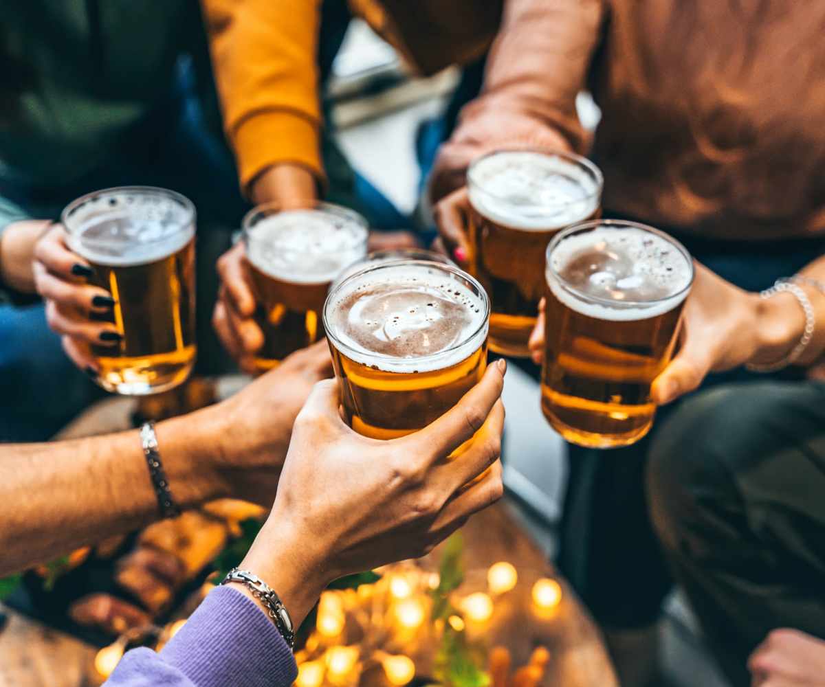 A group of friends celebrating with beer, raising their glasses in a toast near Mazza Grandmarc in College Park, Maryland