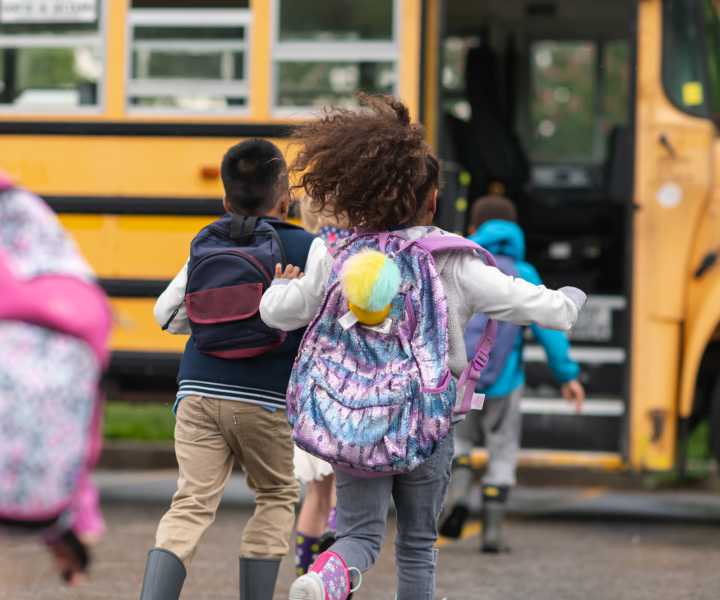 A group of children getting on a school bus near Bernwood Trace in Fort Myers, Florida