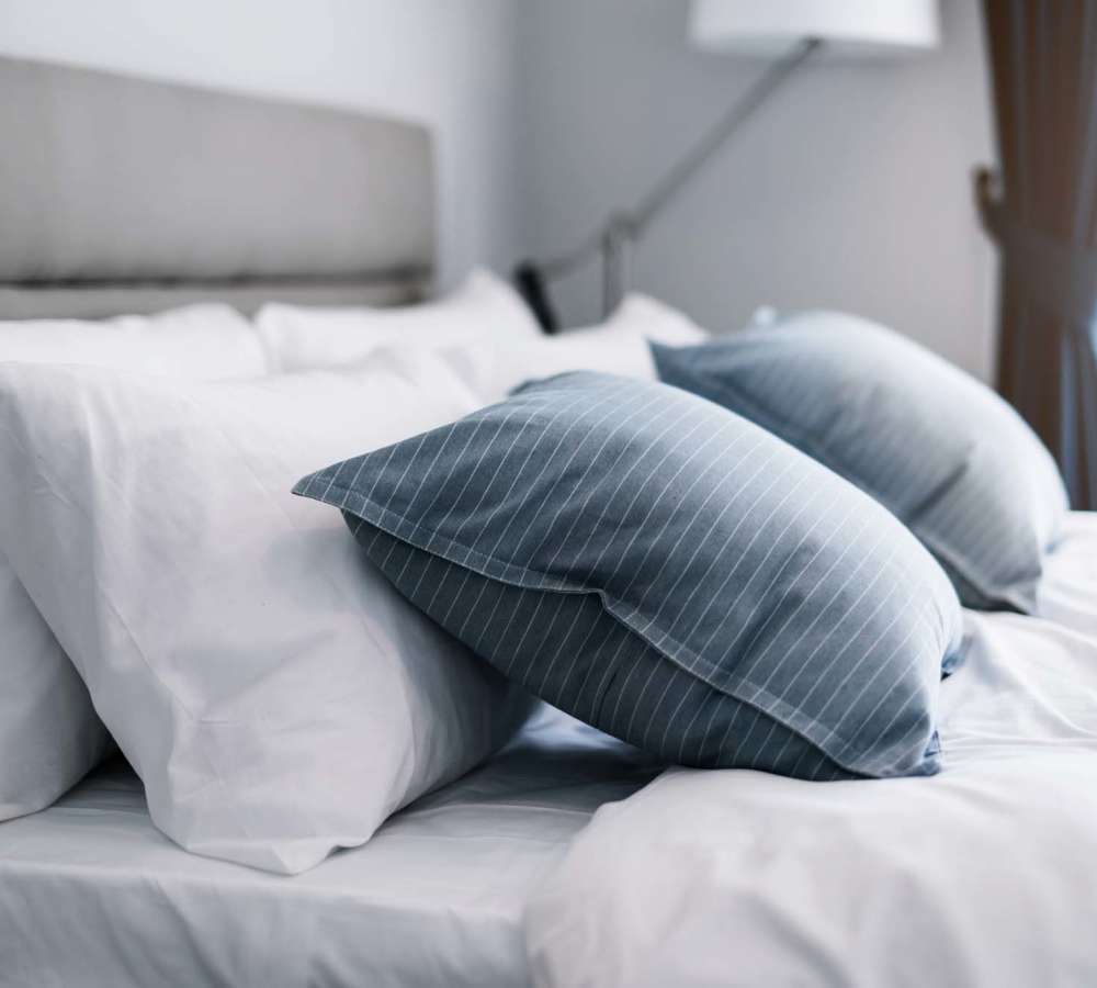 Two blue striped pillows on white bedding at Avia Lofts at Maple Road in Amherst, New York