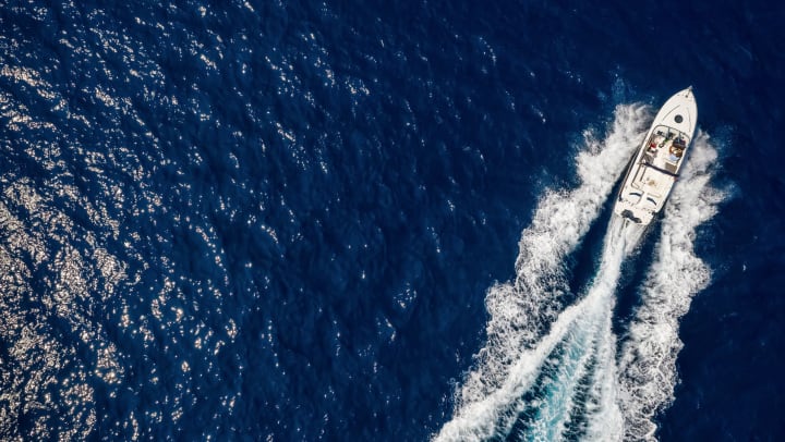 Aerial view of a white boat moving across the ocean.