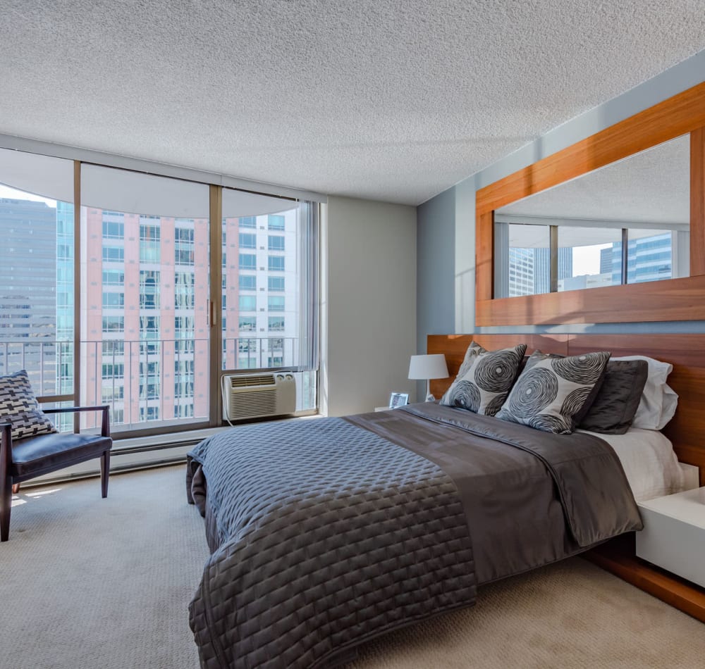 Well-furnished model home's primary suite with floor-to-ceiling windows and a terrific view of the city at Tower 801 in Seattle, Washington
