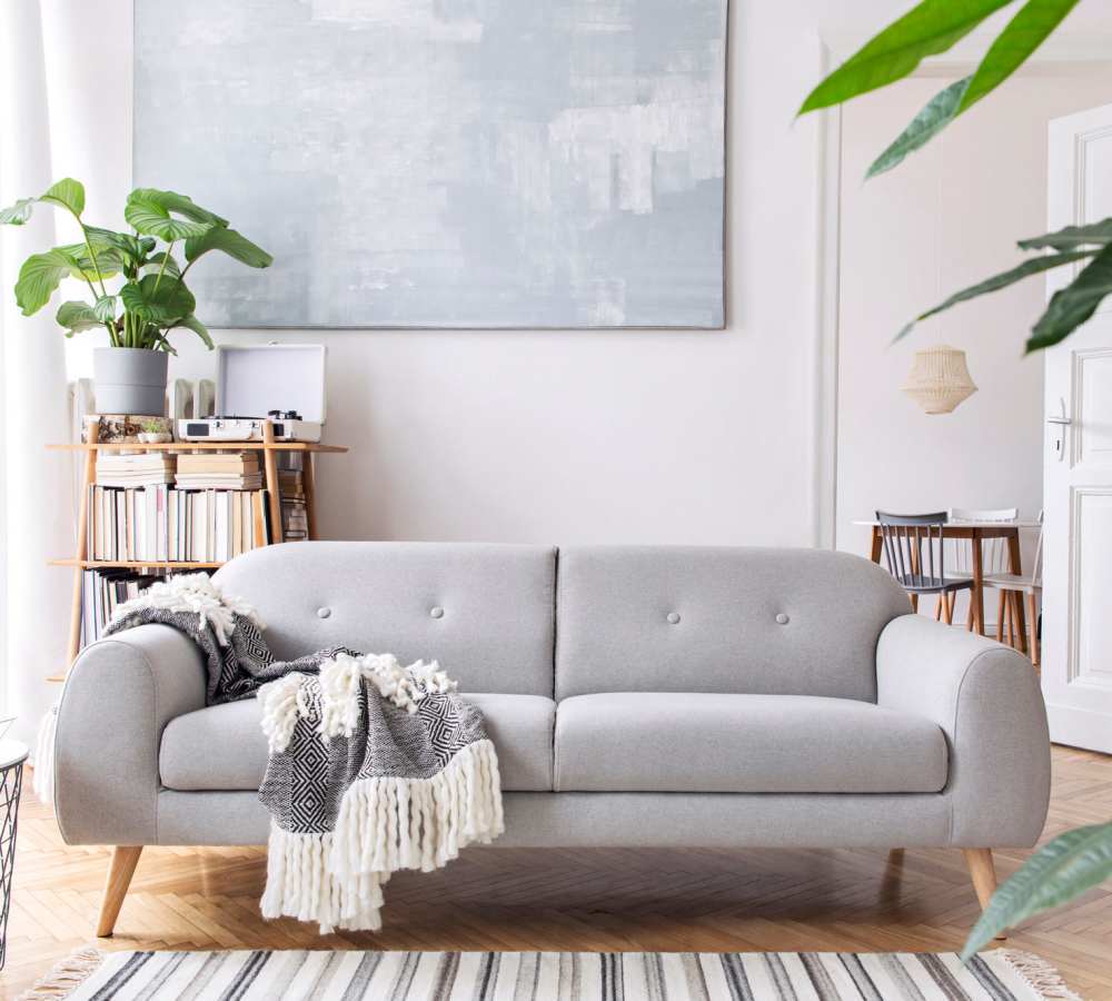 Gray sofa with a blanket draped over it at Avia Lofts at Maple Road in Amherst, New York 