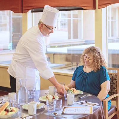 Chef presenting a delicious, fresh-made meal to a resident at Cascade Park Gardens Memory Care in Tacoma, Washington