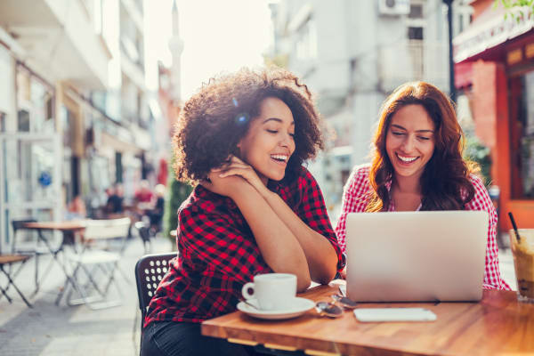 Two young women sitting outside looking at a computer near West Towne in Ames, Iowa