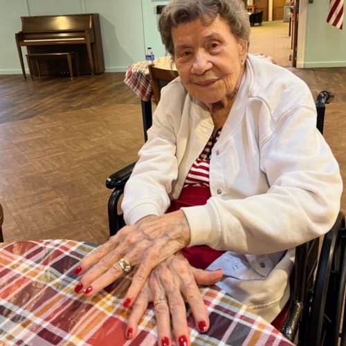 A Resident in a wheelchair sitting outside among falling leaves at Oxford Glen Memory Care at Sachse in Sachse, Texas