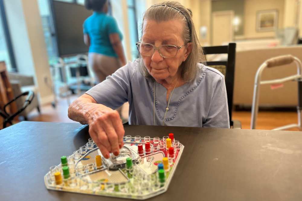 Elderly woman enjoying a board game at The Barclay at Charlottesville in Charlottesville, Virginia.