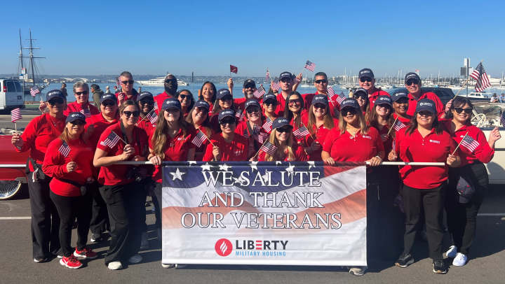 Group picture of Liberty Military Housing team members at the San Deigo Fleet Week Veterans Parade holding a banner that reads "We Salute and Thank our Veterans"
