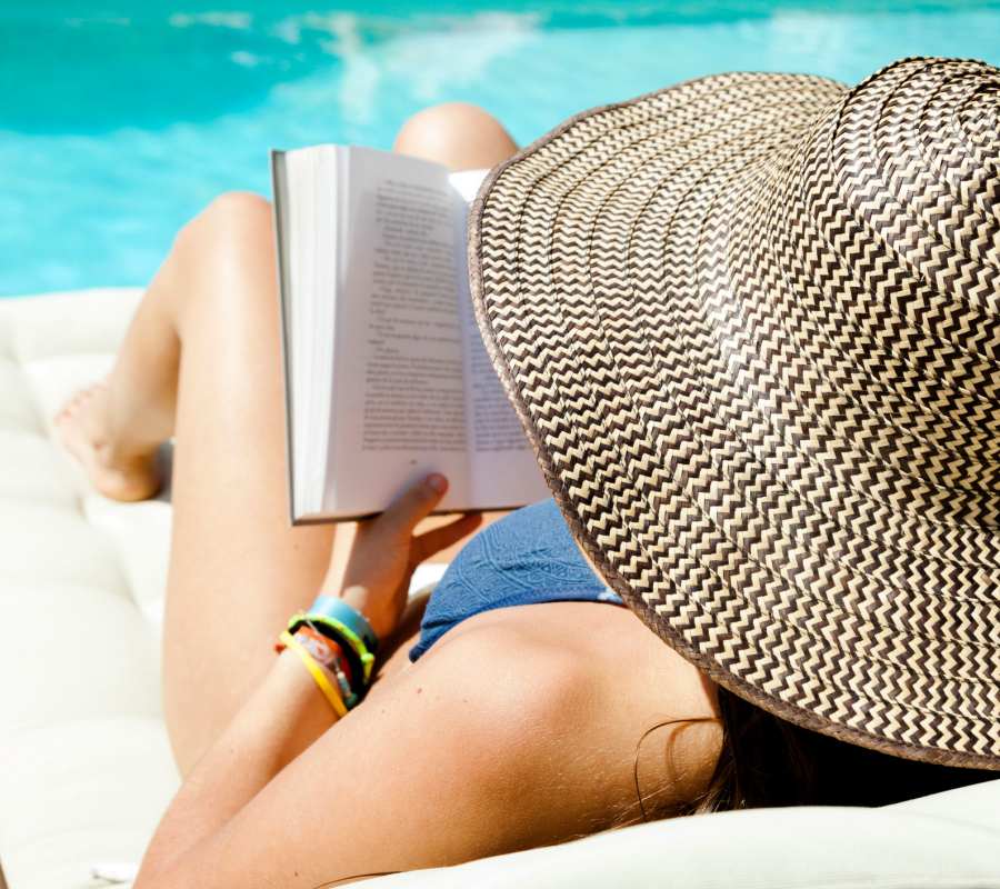Woman with a hat reading a book by the pool at The Overlook at Keystone Canyon in Reno, Nevada