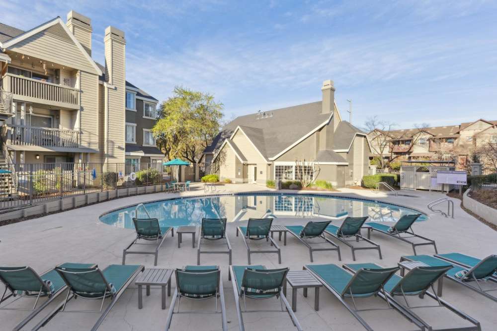 Spacious sundeck with table and chairs next to a swimming pool at Mill Springs Park Apartment Homes in Livermore, California