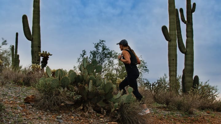  Woman hiking in the desert with cacti around her. 