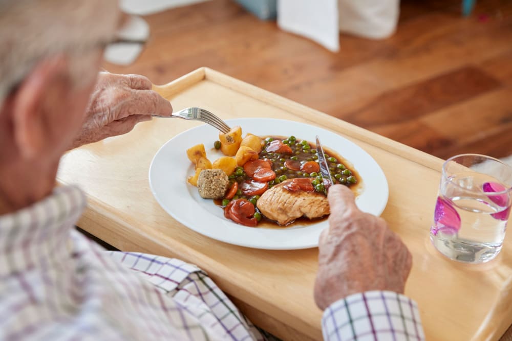 A resident cutting into his chicken and vegetables meal 