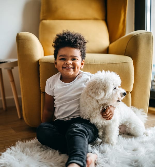 A young child sitting on the floor with his small dog at Riverstone in Macon, Georgia