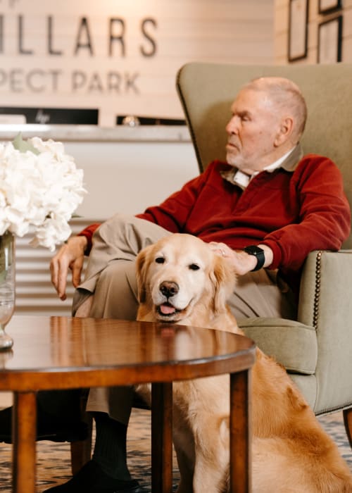 Resident sitting in the lounge with golden retriever at The Pillars of Prospect Park in Minneapolis, Minnesota
