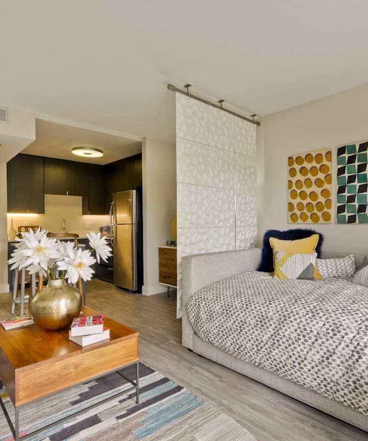 Bedroom and living areas with the kitchen in the background in an open-concept model studio home at Mia in Palo Alto, California