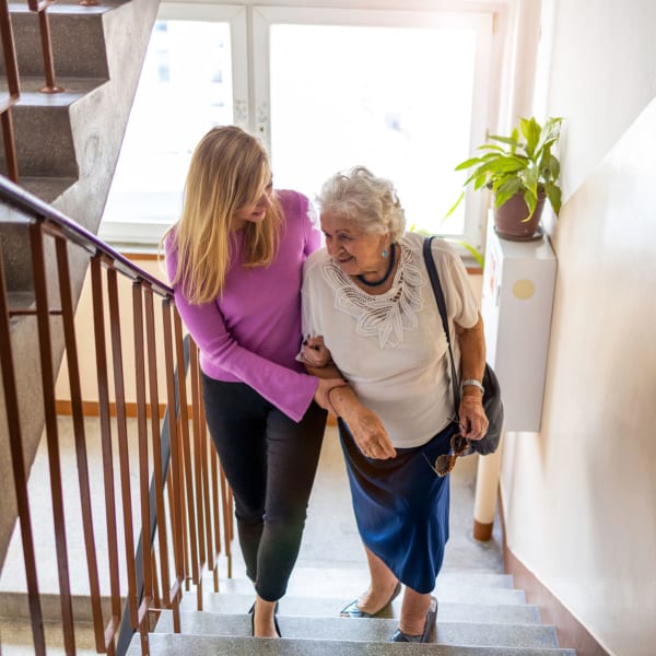 A staff member helping a resident up some stairs at Pacifica Senior Living Bonita in Chula Vista, California