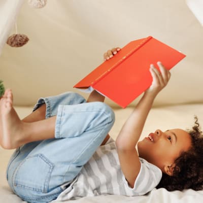 A resident child reading a book at Santa Fe Apartment Homes in Dallas, Texas