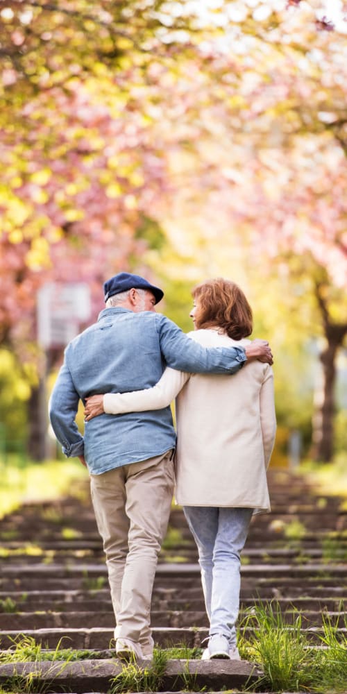 A resident couple walking along an outdoor path in the Fall season while embracing