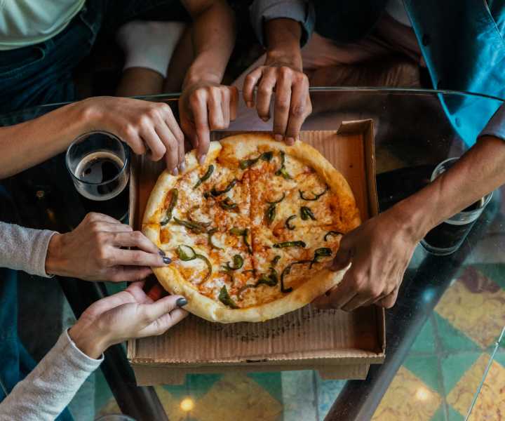 Group of residents sharing a pizza at a restaurant near Pelican Isles Apartments in Sebastian, Florida