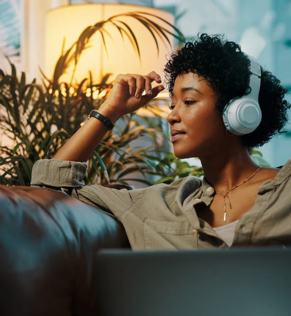 A resident relaxing on her couch with headphones on at The Station at Brighton in Grovetown, Georgia