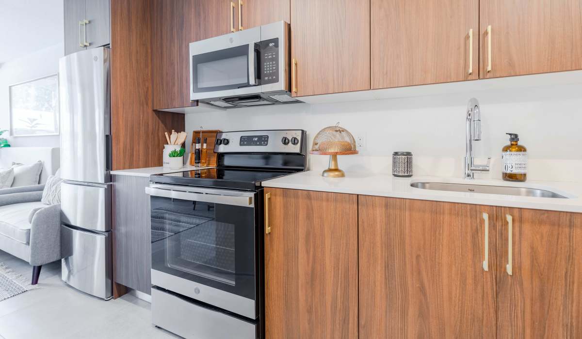 Spacious kitchen with wooden cabinetry, range and refrigerator at Alture Westland in Hialeah, Florida