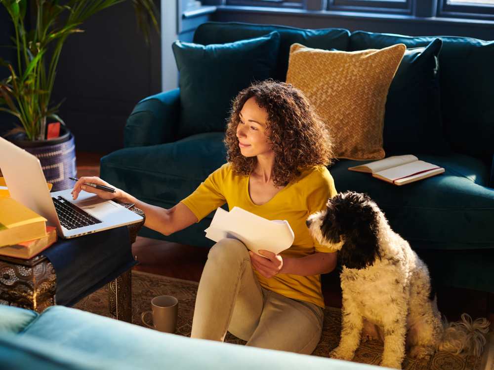Woman working on laptop with dog beside her at Runaway Bay in Lansing, Michigan