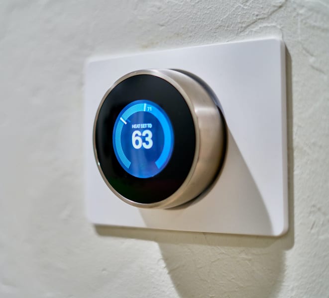 a smart thermostat in a home reading 63 degrees