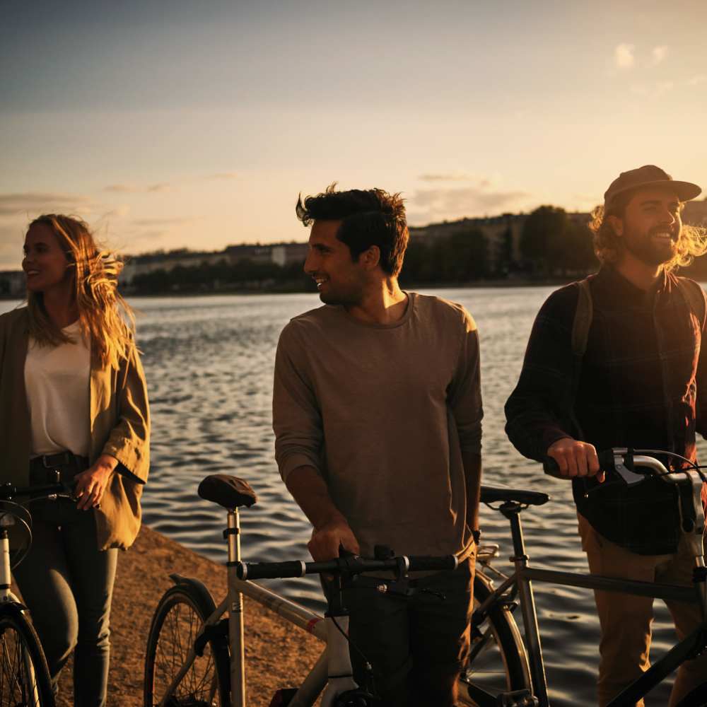Three friends walking their bikes beside the waterfront near DECRO Long Beach in Long Beach, California