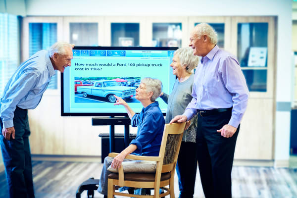 Residents interacting with touch screen computer at Golden Pond Retirement Community laughing in Sacramento, California