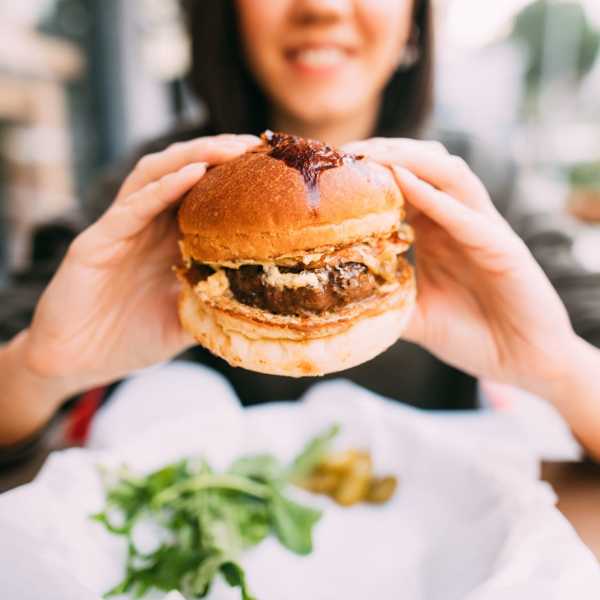 Woman eating burger near Mayflower Harbor at Pilgrims Landing in Lehi, Utah