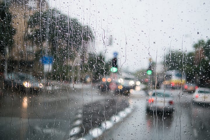 A rainy street scene as seen through a rainy window. 