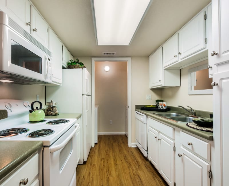 Bright kitchen with hardwood flooring and bright white appliances in a model home at Waterfield Court Apartment Homes in Aurora, Colorado