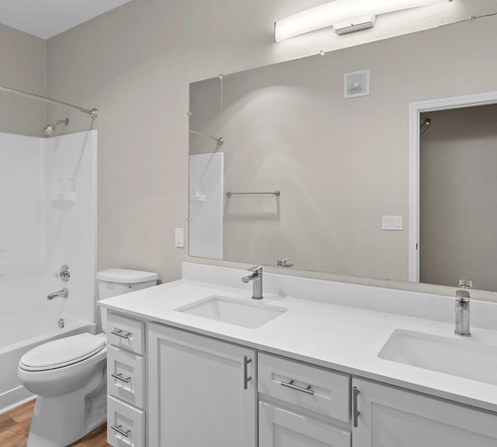 Bathroom with double sinks, white cabinets, and white counters